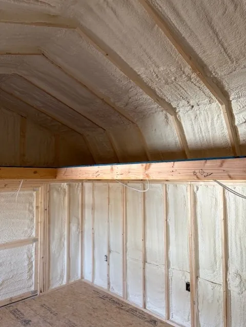 Close-up of spray foam insulation covering the peak of a vaulted commercial building ceiling