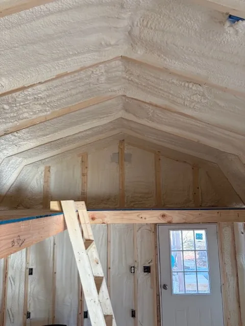 Closed-cell spray foam covering the walls and vaulted ceiling of a completed commercial building interior