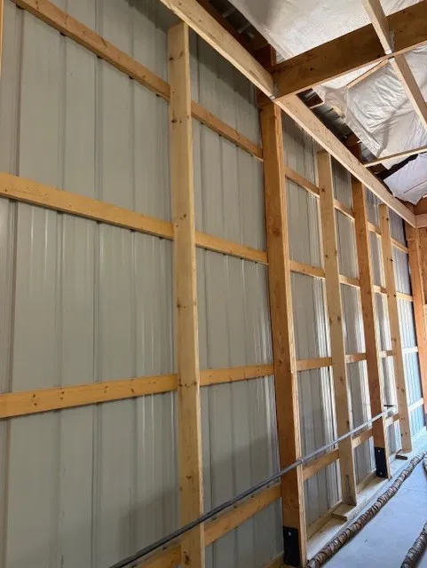 Framed garage interior with open wall studs ready for spray foam insulation before drywall