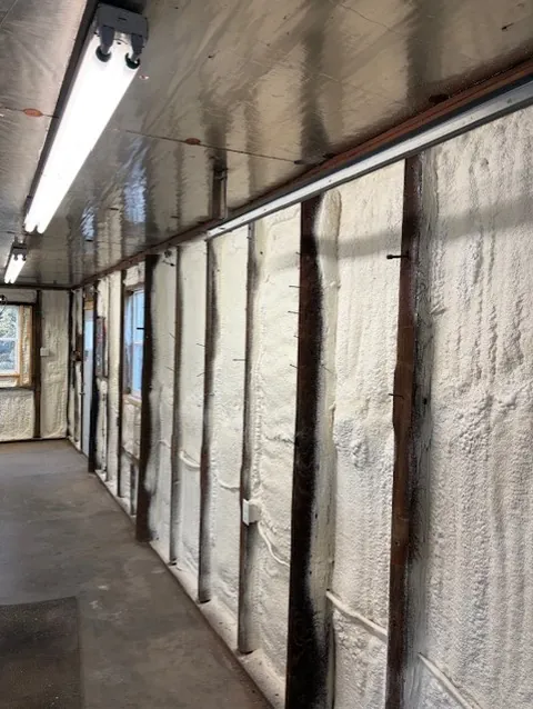 Interior of a building with spray foam insulation applied to walls and ceiling along a long hallway